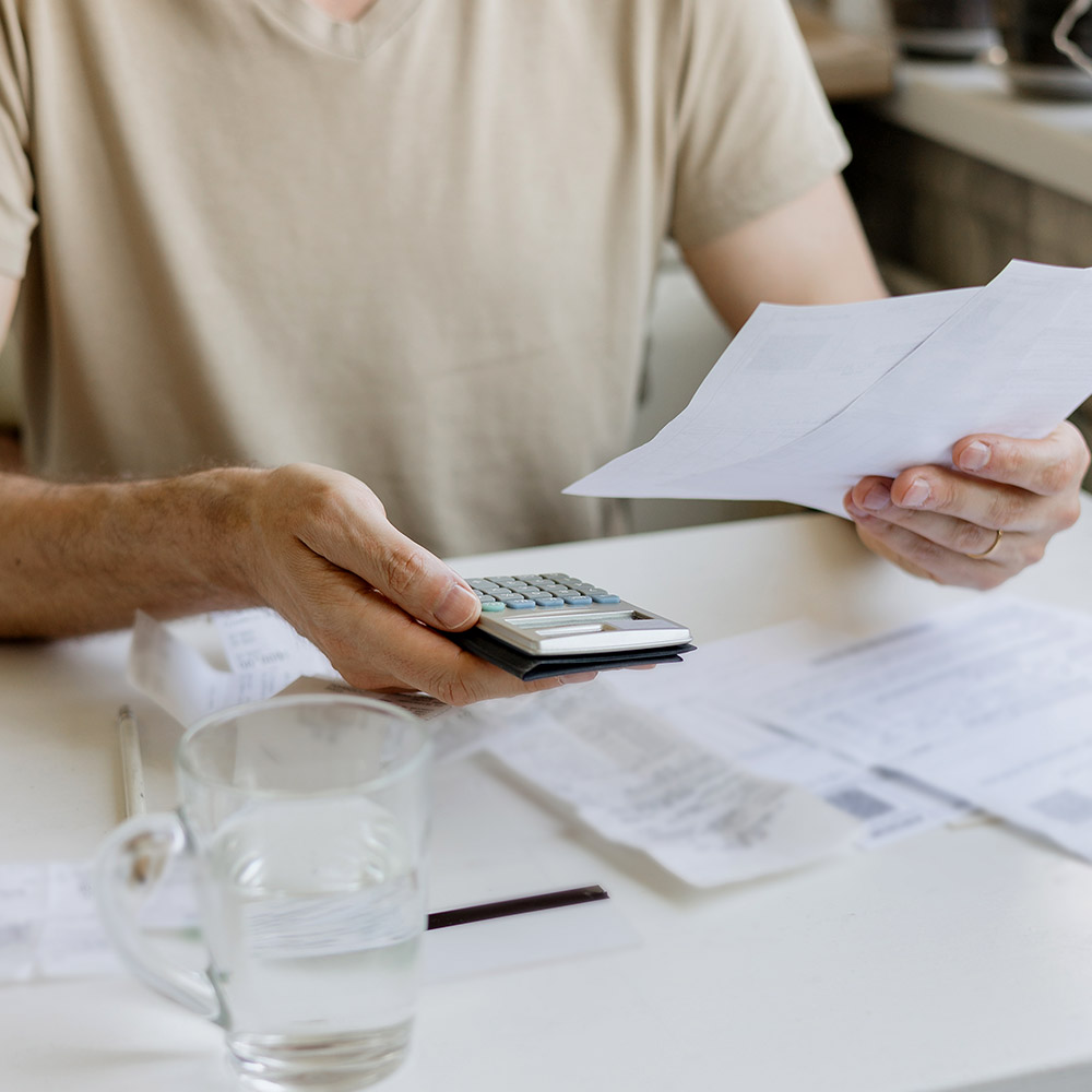Burst Pipes Man reviewing an unexpectedly high water bill with a calculator, suggesting a hidden burst pipe or water leak that needs professional detection by AP Plumbing and Electrical Services